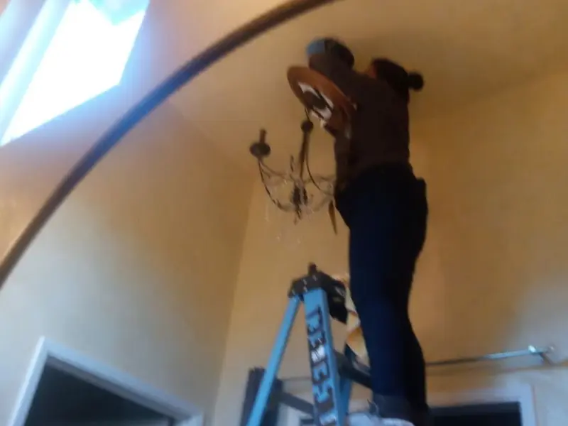 Electrician installing a chandelier in a Westchester residence